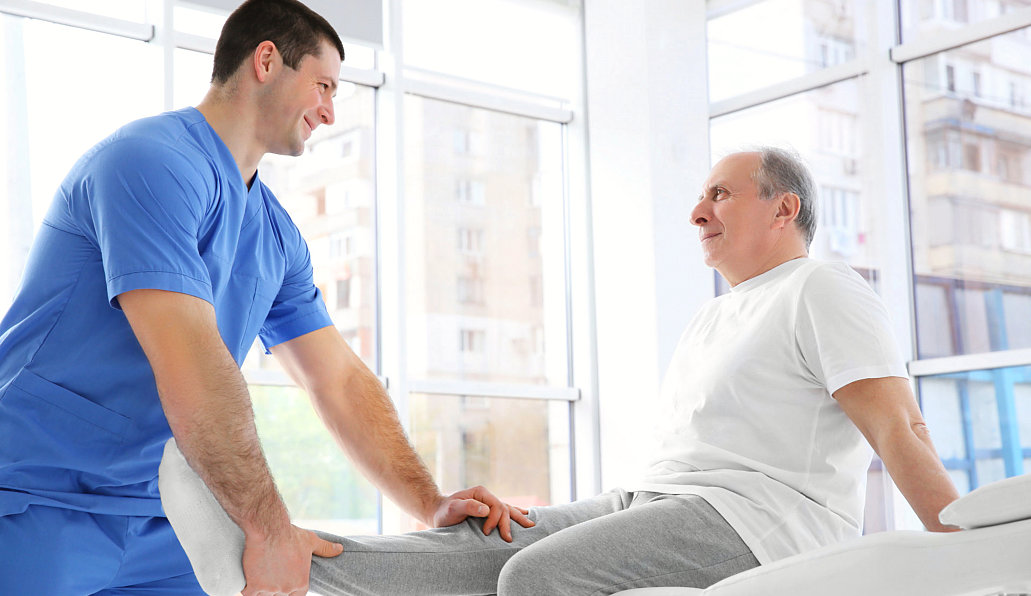 caregiver assisting senior man to his leg